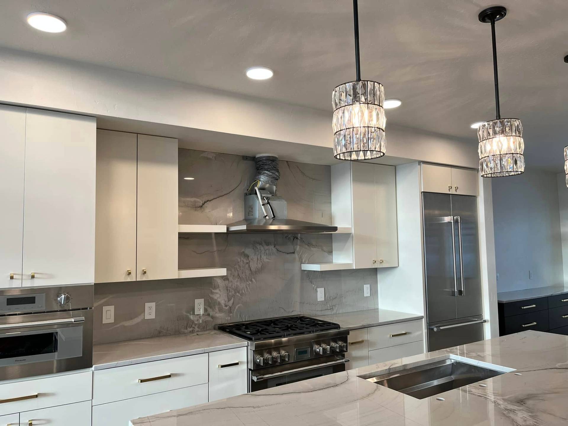 Modern white kitchen with brass hardware and marble backsplash